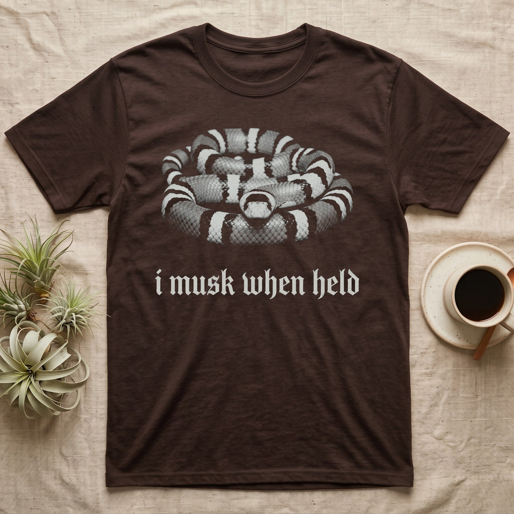 Milk Snake Musk T-Shirt in Dark Chocolate — One-ink photo of a calm milk snake facing forward on its coils, above the blackletter line i musk when held