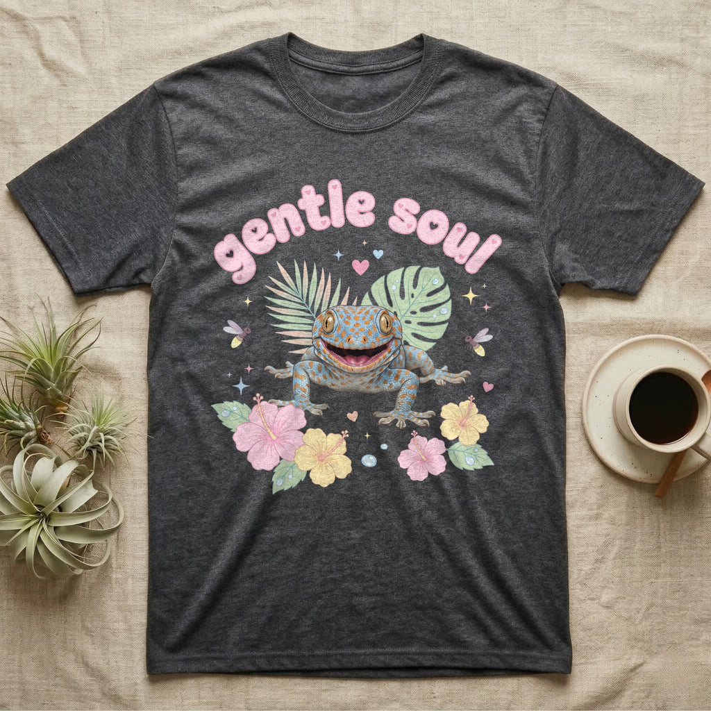 Tokay Gecko Baby T-Shirt in Dark Heather — Blue-and-orange spotted tokay gecko among pastel leaves and hibiscus under puffy pink bubble text "gentle soul".