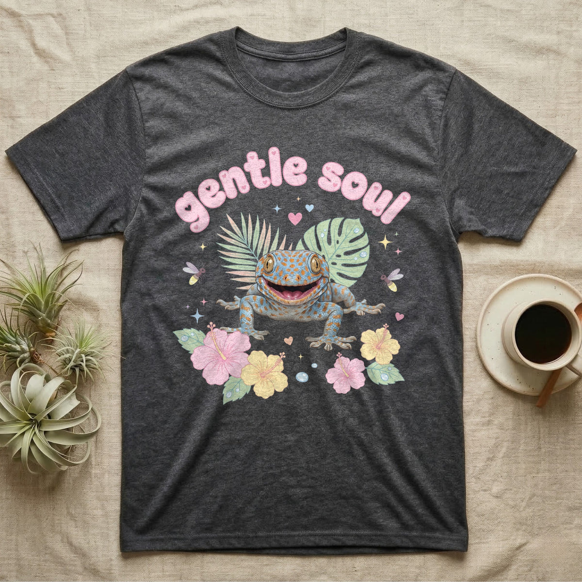 Tokay Gecko Baby T-Shirt in Dark Heather — Blue-and-orange spotted tokay gecko among pastel leaves and hibiscus under puffy pink bubble text "gentle soul".
