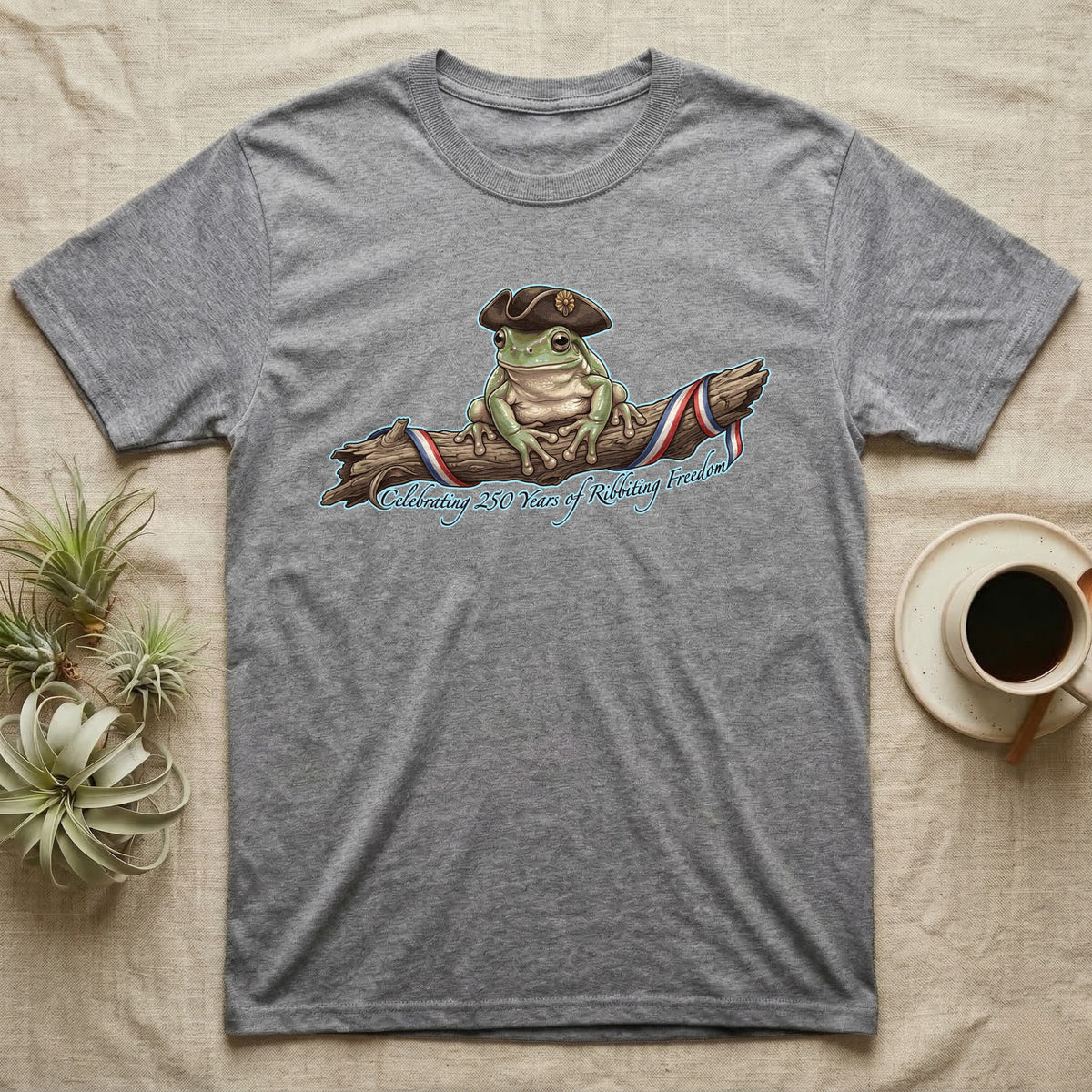 Tree Frog Freedom T-Shirt in Sport Grey — Detailed green tree frog in a tricorn hat on a ribboned branch under script Celebrating 250 Years of Freedom.