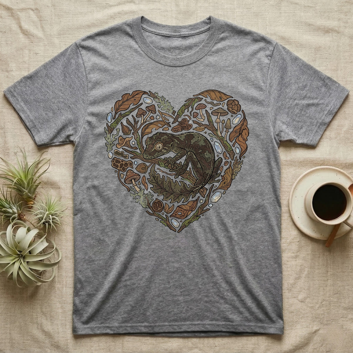 Grey t-shirt with heart-shaped naturalistic illustration of a gecko and leaves.