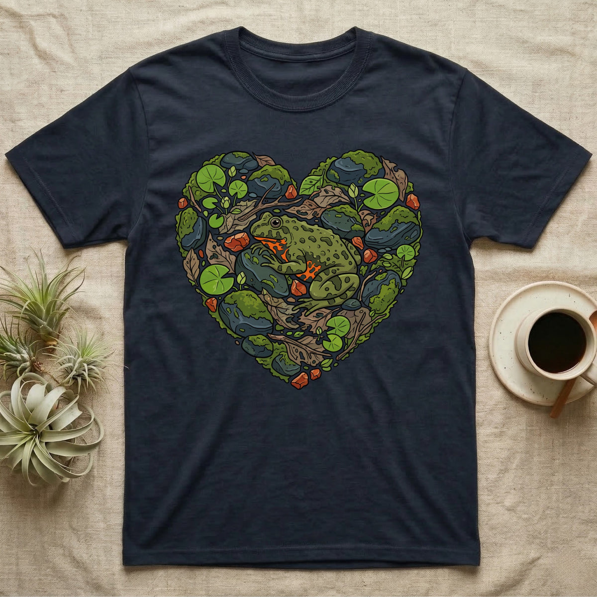 Dark t-shirt with a green frog and mossy rocks forming a heart shape.