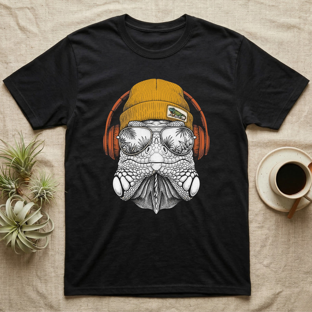 Green Iguana Headphones T-Shirt in Black — Engraved green iguana with jowls and dorsal spines in a beanie and headphones, aviators reflecting a rainforest.