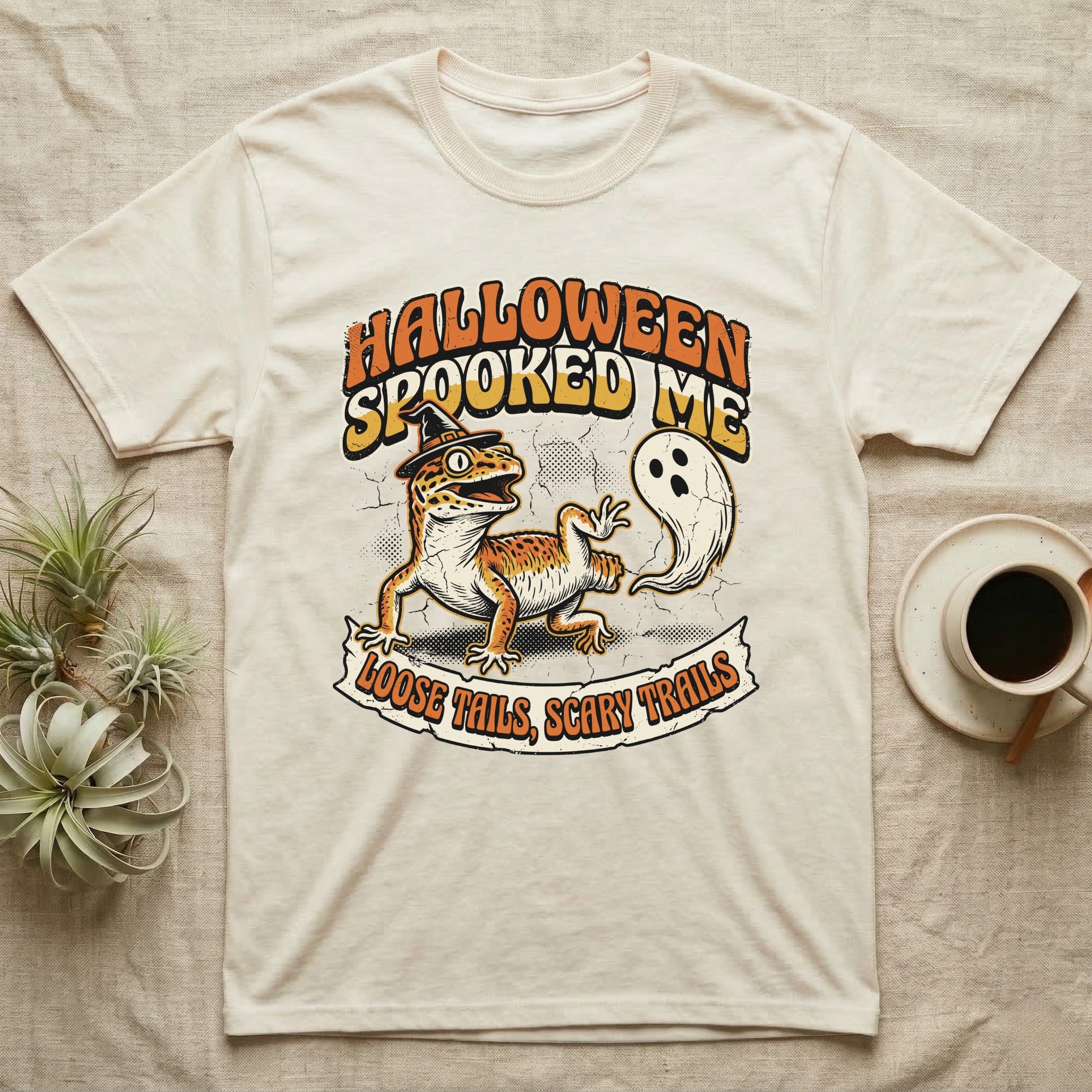 Leopard Gecko Spooked Me T-Shirt in Natural — Distressed graphic of a shocked leopard gecko in a witch hat beside its ghost-costumed dropped tail, "Halloween Spooked Me."