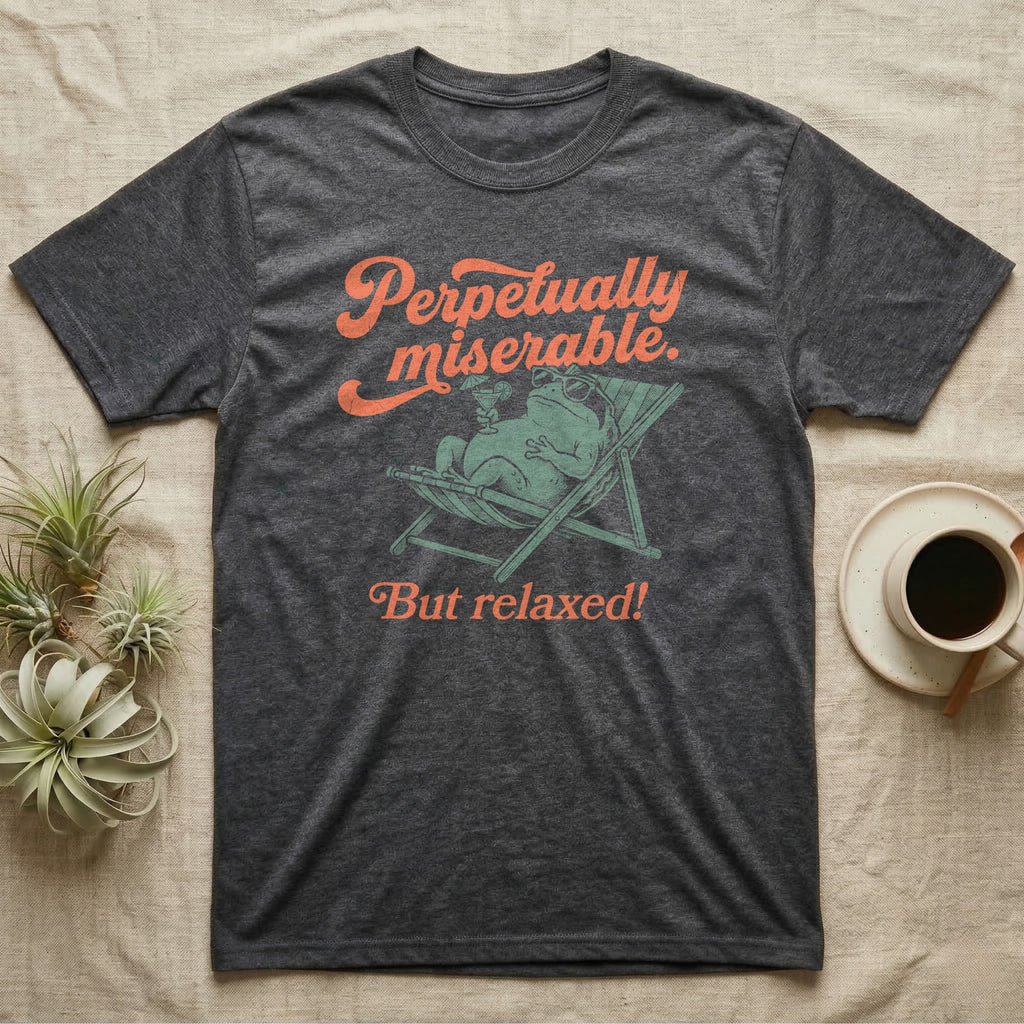 Desert Rain Frog Grump Mode T-Shirt in Dark Heather — Illustrated desert rain frog lounging in a beach chair with sunglasses and a cocktail, coral script reading Perpetually Miserable But Relaxed.
