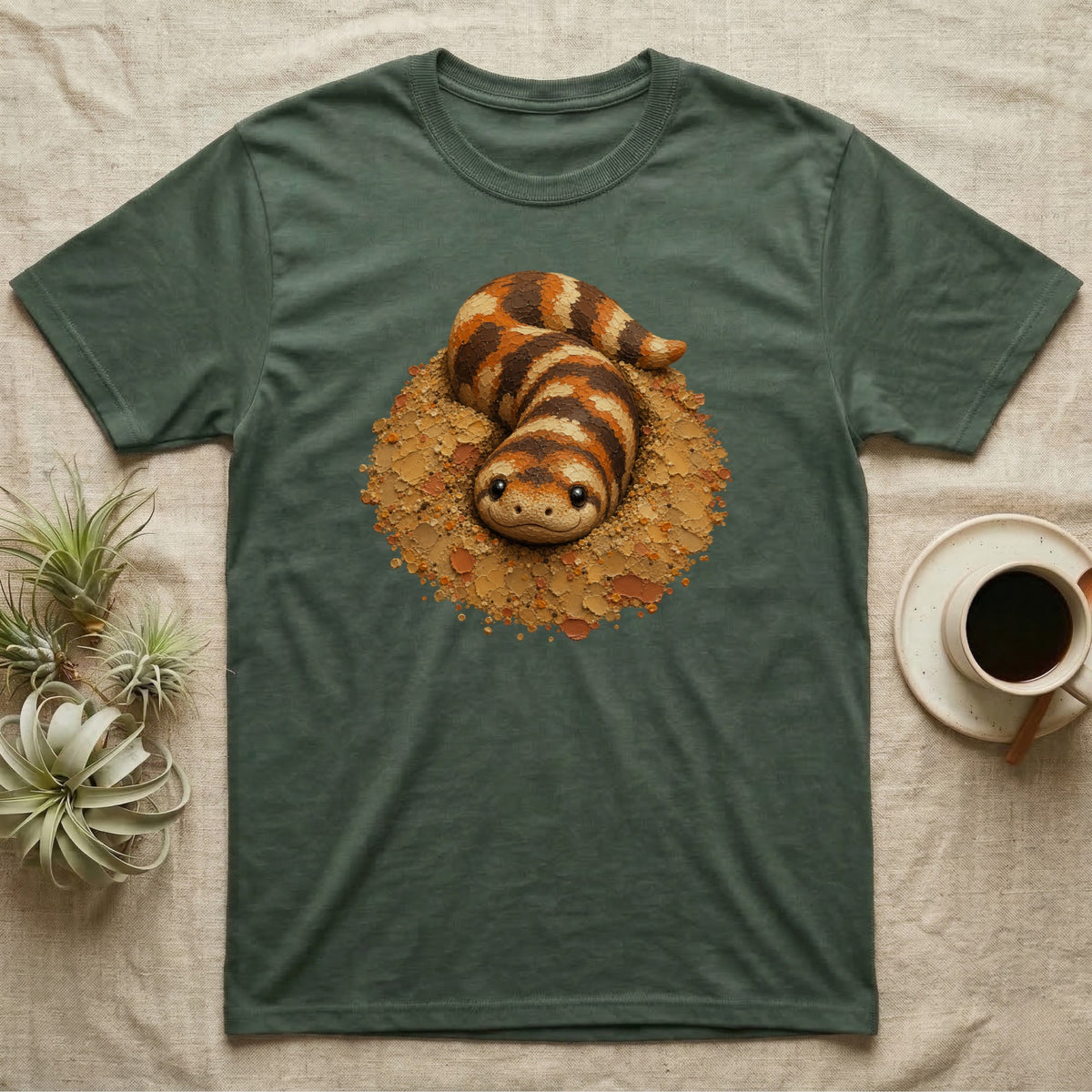 Green t-shirt with a cartoon snake nestled in a dirt mound.