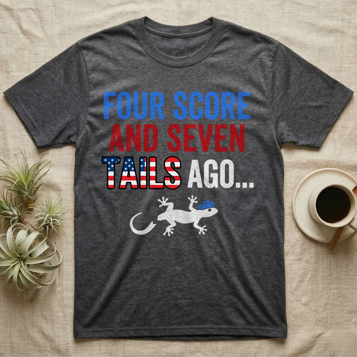 Gecko Four Score T-Shirt in Dark Heather — Block text Four Score and Seven Tails Ago with a flag-filled word above a white gecko silhouette shedding its tail.