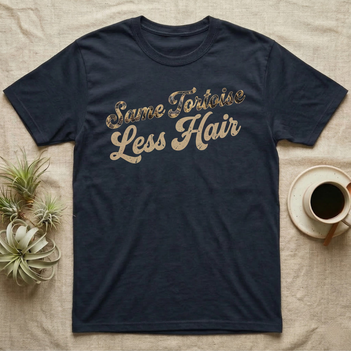 Tortoise Owner Retro T-Shirt in Navy — Worn 1970s brush script reading Same Tortoise in tortoise-shell texture over Less Hair in warm sand, climbing a diagonal on charcoal grey