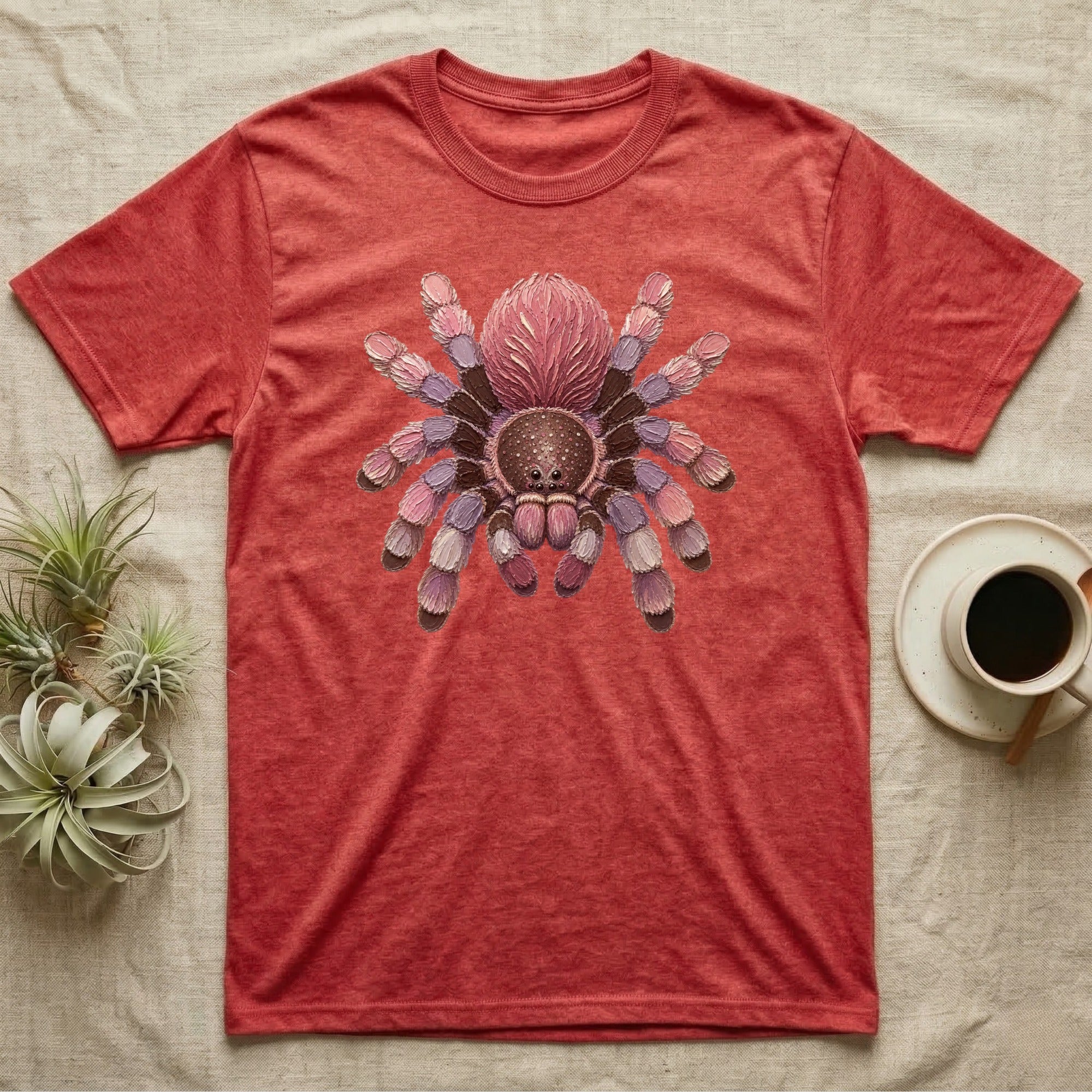 Red t-shirt with a colorful tarantula graphic on chest, coffee cup nearby.