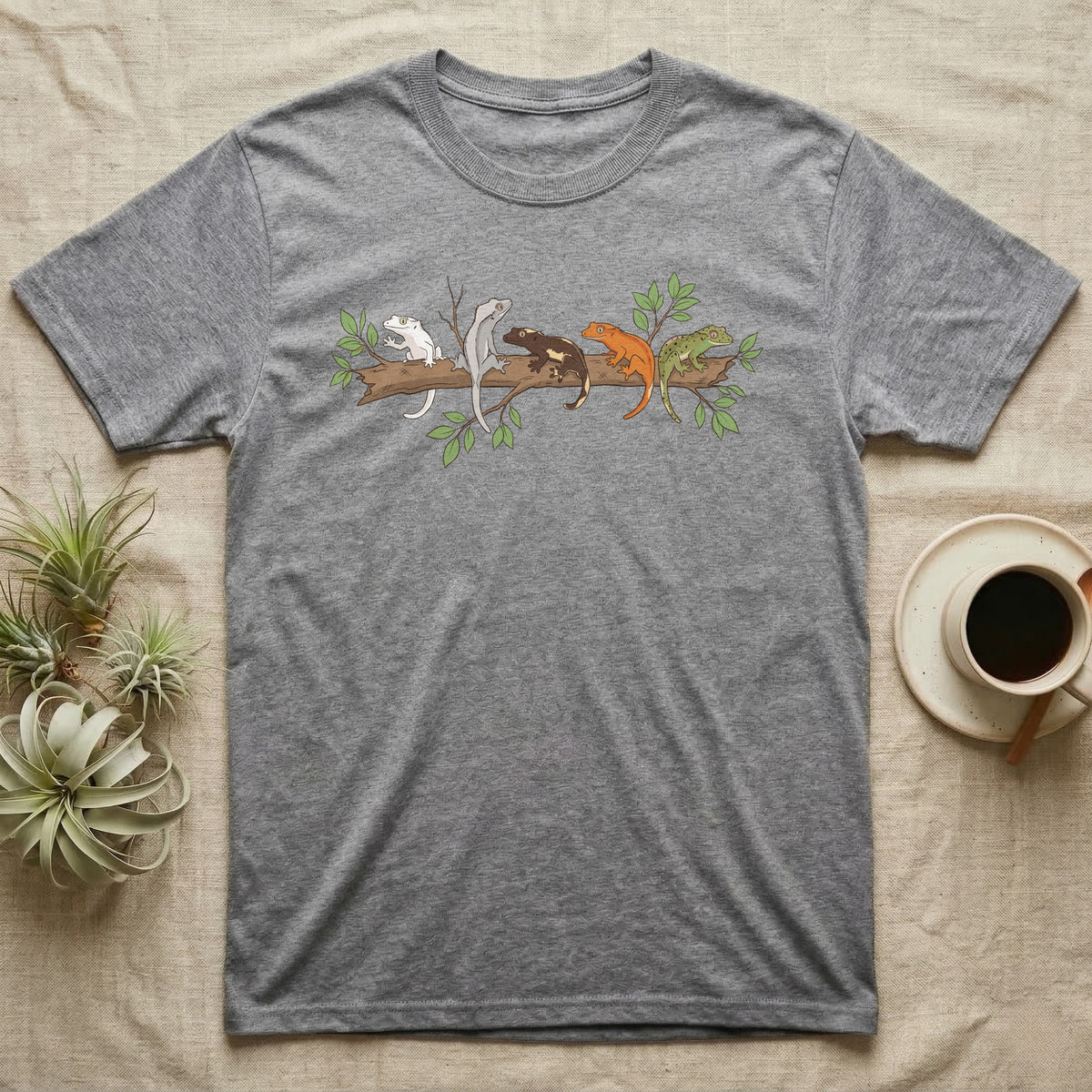 Crested Gecko Morph Line T-Shirt in Sport Grey — Five crested gecko morphs in ink and watercolour perched along one cork bark branch with ficus leaves.