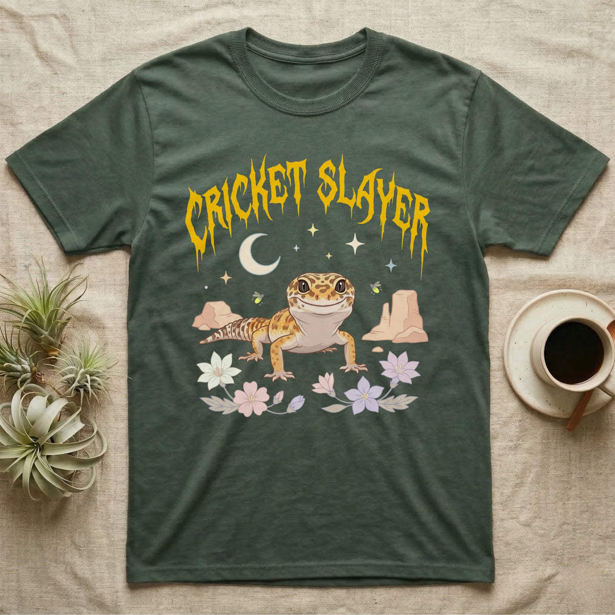 Leopard Gecko Feral T-Shirt in Military Green — Smiling leopard gecko in a pastel desert-night scene under a spiky golden metal wordmark reading CRICKET SLAYER.