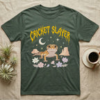 Leopard Gecko Feral T-Shirt in Military Green — Smiling leopard gecko in a pastel desert-night scene under a spiky golden metal wordmark reading CRICKET SLAYER.