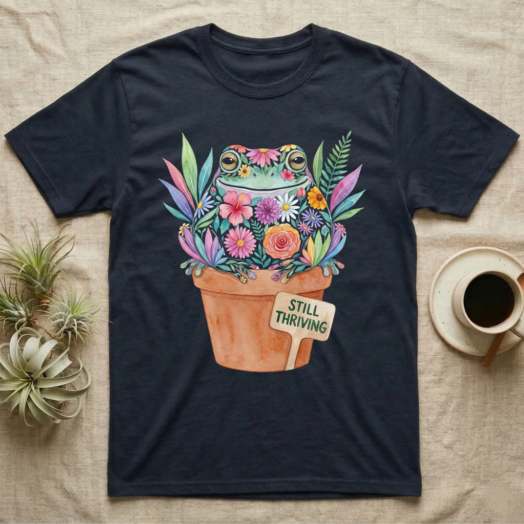 Tree Frog Thriving T-Shirt in Navy — A White's tree frog made of watercolour flowers, sitting in a terracotta pot with a plant label reading STILL THRIVING.