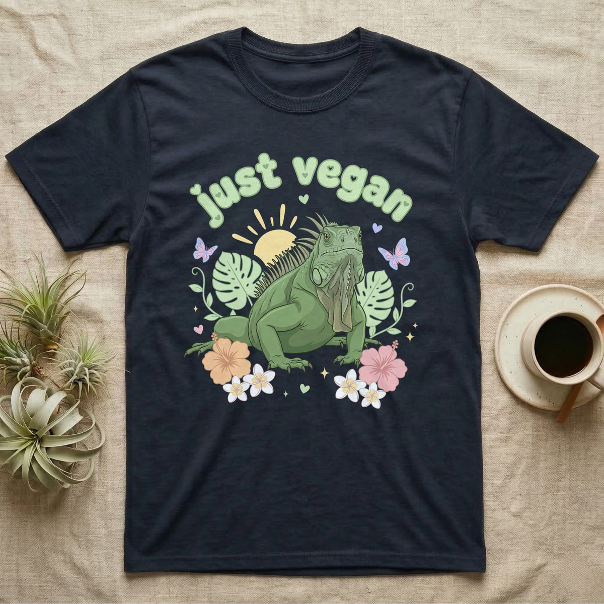 Green Iguana Baby T-Shirt in Navy — Green iguana with spiky crest and dewlap among pastel leaves and flowers under puffy green bubble text "just vegan".