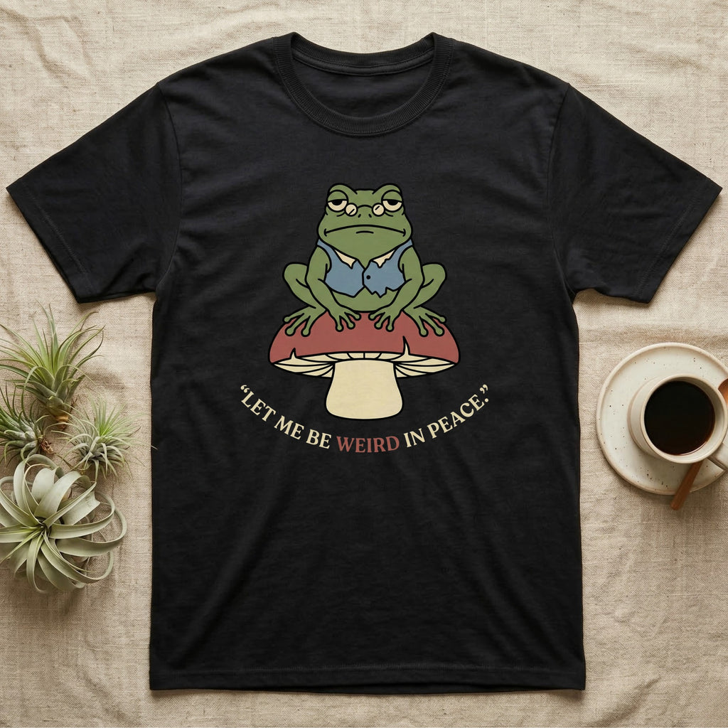 Black t-shirt with frog sitting on a mushroom, "Let me be weird in peace" text.