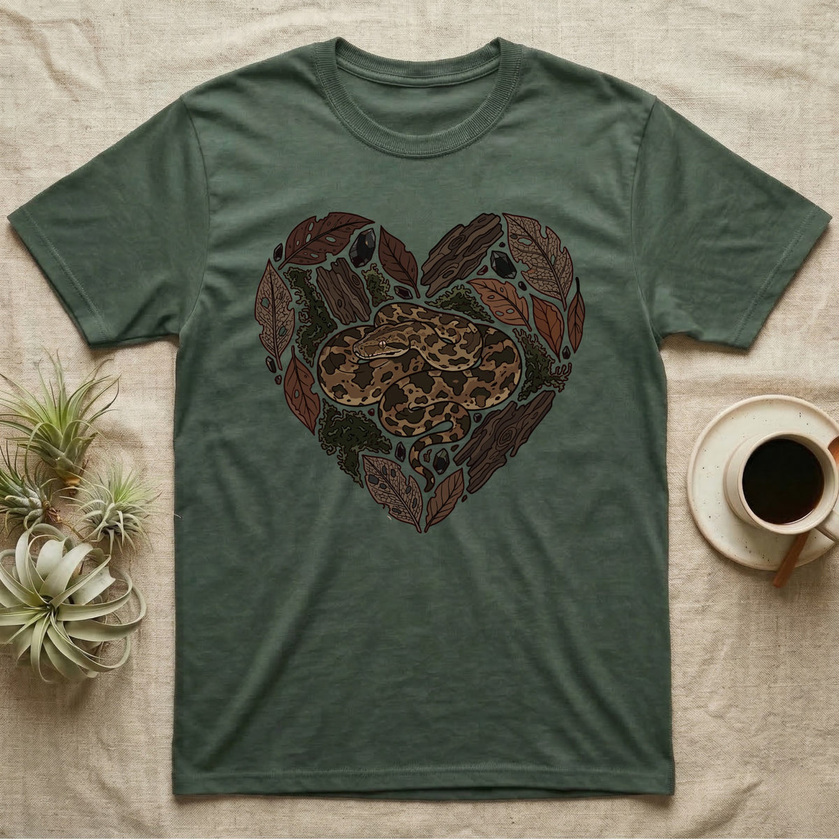 Green t-shirt with a snake and natural elements forming a heart.