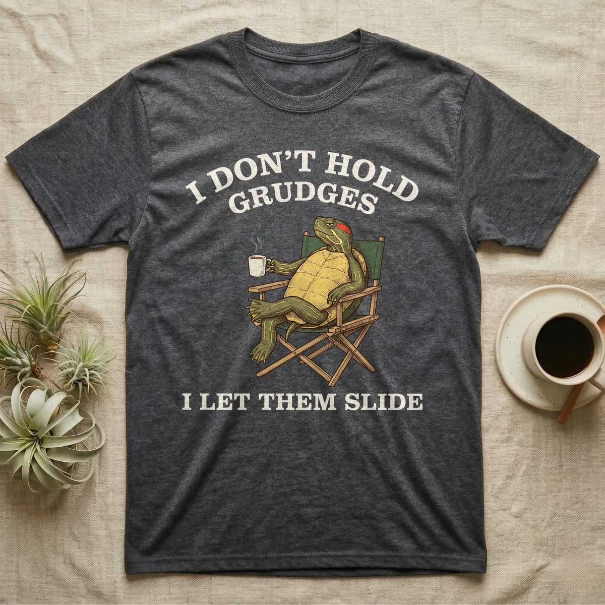 Red-Eared Slider Grudges T-Shirt in Dark Heather — Engraved red-eared slider lounging in a camp chair with tea under I Don't Hold Grudges I Let Them Slide