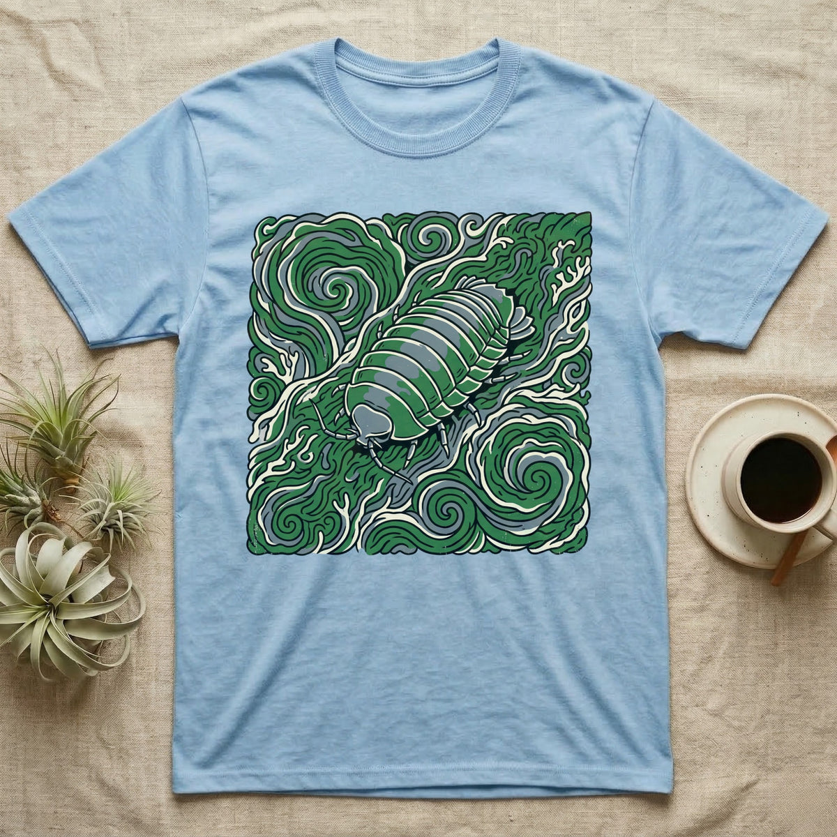 Light blue t-shirt with a green pill bug design on a swirling green background.