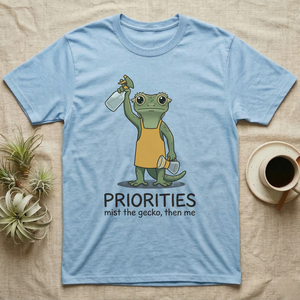 Crested Gecko Coffee T-Shirt in Light Blue — Storybook crested gecko standing with a raised spray mister and a pour-over coffee, text priorities below