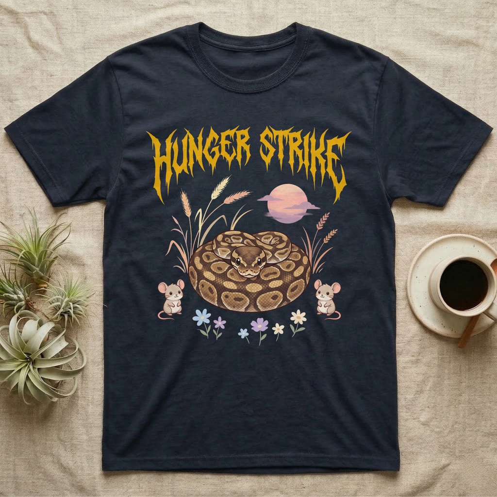 Ball Python Feral T-Shirt in Navy — Ball python coiled in a loaf in a pastel savanna scene under a spiky honey-gold metal wordmark reading HUNGER STRIKE.