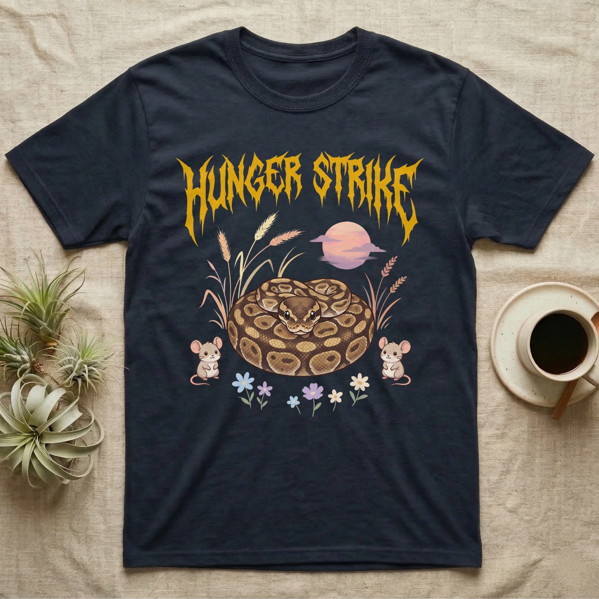 Ball Python Feral T-Shirt in Navy — Ball python coiled in a loaf in a pastel savanna scene under a spiky honey-gold metal wordmark reading HUNGER STRIKE.
