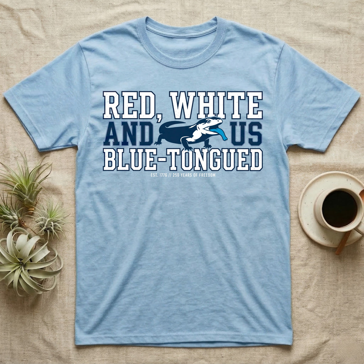 Blue-Tongued Skink 1776 T-Shirt in Light Blue — Navy and white blue-tongued skink with tongue out between collegiate text reading Red, White and US Blue-Tongued.