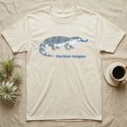 Cream t-shirt with stylized blue-tongue lizard graphic and text.