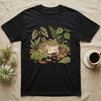 Bioactive Pacman Frog T-Shirt in Black — Warm botanical illustration of a content pacman frog half-buried in a lush bioactive habitat of moss and leaf litter.
