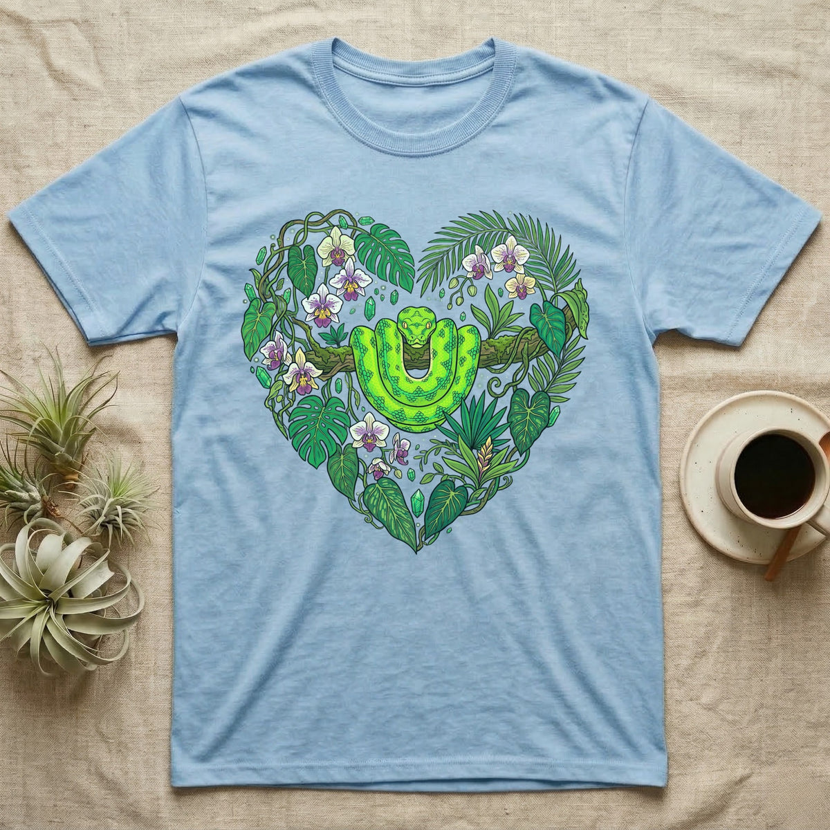 Light blue t-shirt with a green snake and tropical plants forming a heart.