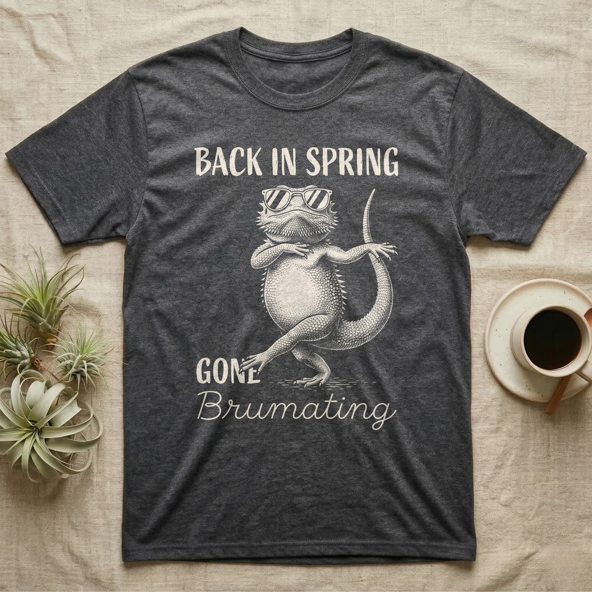 Bearded Dragon Brumating T-Shirt in Dark Heather — Bearded dragon in striped sunglasses doing a dance step, retro text reads Back In Spring, Gone Brumating