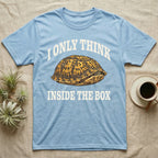 Box Turtle Thinker T-Shirt in Light Blue — Engraved eastern box turtle shut in its shell, one eye peeking out, under I Only Think Inside the Box