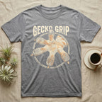 Macro badge illustration of a gecko's splayed foot with ribbed adhesive toe pads inside a distressed circular border, arched wordmark reading GECKO GRIP. — shown on a Sport Grey tee.