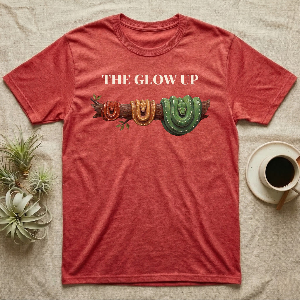 Green Tree Python Glow-Up T-Shirt in Heather Red — Impasto illustration of a green tree python at three life stages on one branch: red hatchling, orange-brown subadult, green adult.