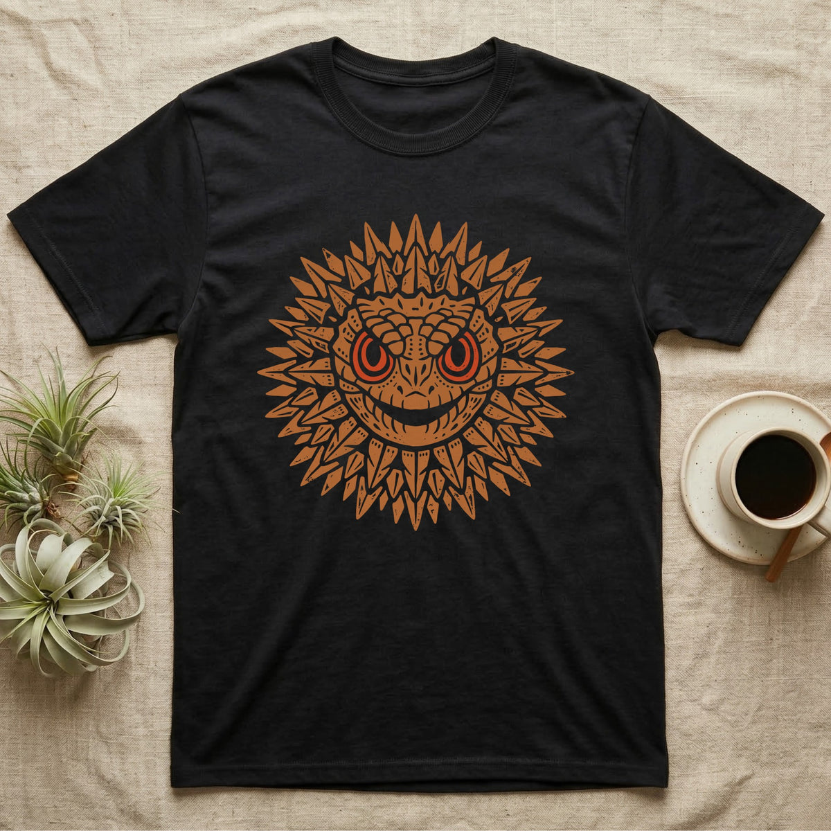 Crocodile Skink Tiny Dragon T-Shirt in Black — Frontal red-eyed crocodile skink head with dorsal spines flared into an ochre sunburst medallion, red eye ring.