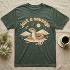 Kenyan Sand Boa Softie T-Shirt in Military Green — Kenyan sand boa looping out of pastel sand dunes under a puffy "just a sausage" bubble wordmark with tiny hearts.