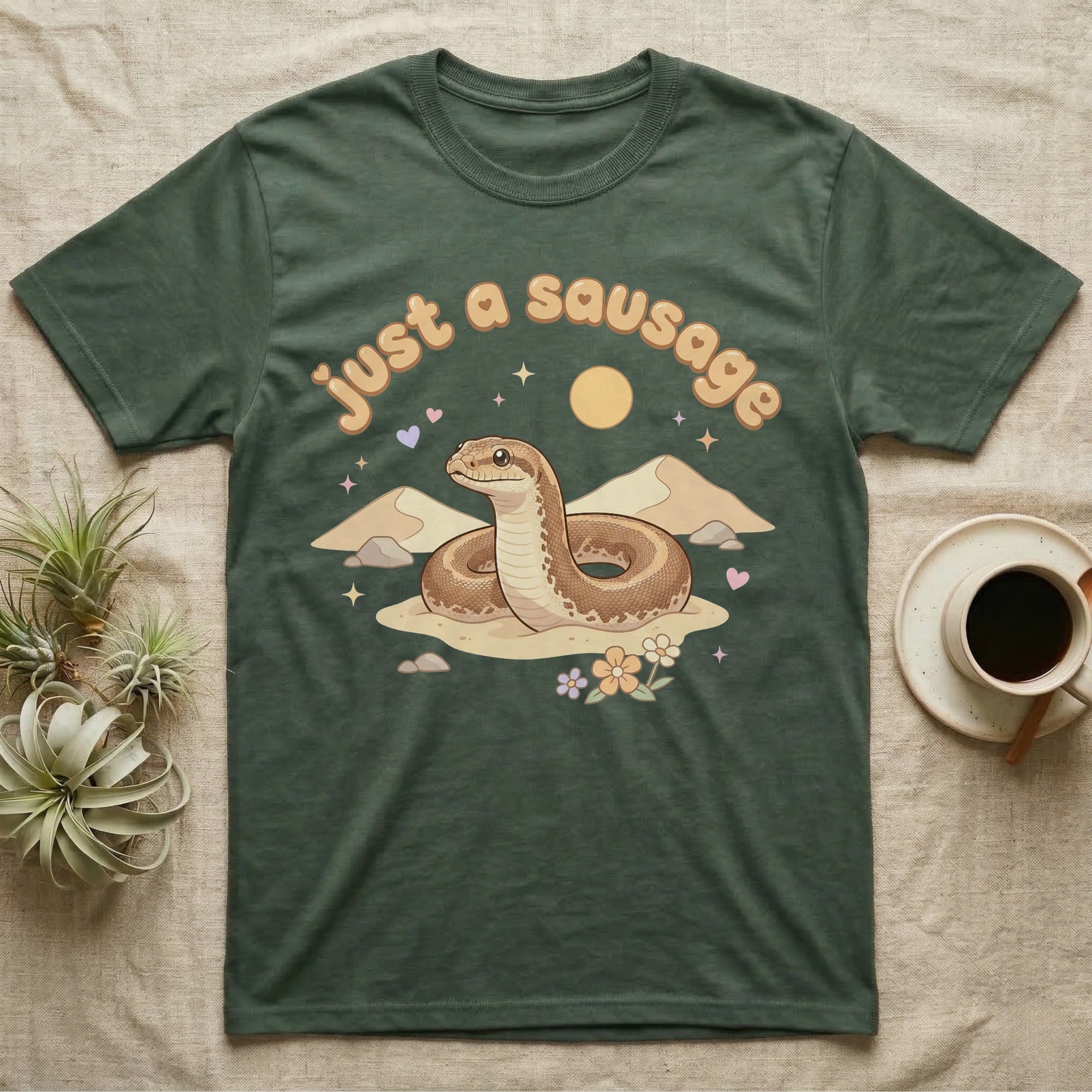 Kenyan Sand Boa Softie T-Shirt in Military Green — Kenyan sand boa looping out of pastel sand dunes under a puffy "just a sausage" bubble wordmark with tiny hearts.