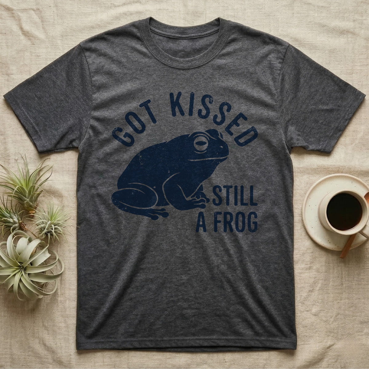 Tree Frog Kissed T-Shirt in Dark Heather — Worn navy silhouette of a dumpy White's tree frog under the words Got Kissed Still A Frog