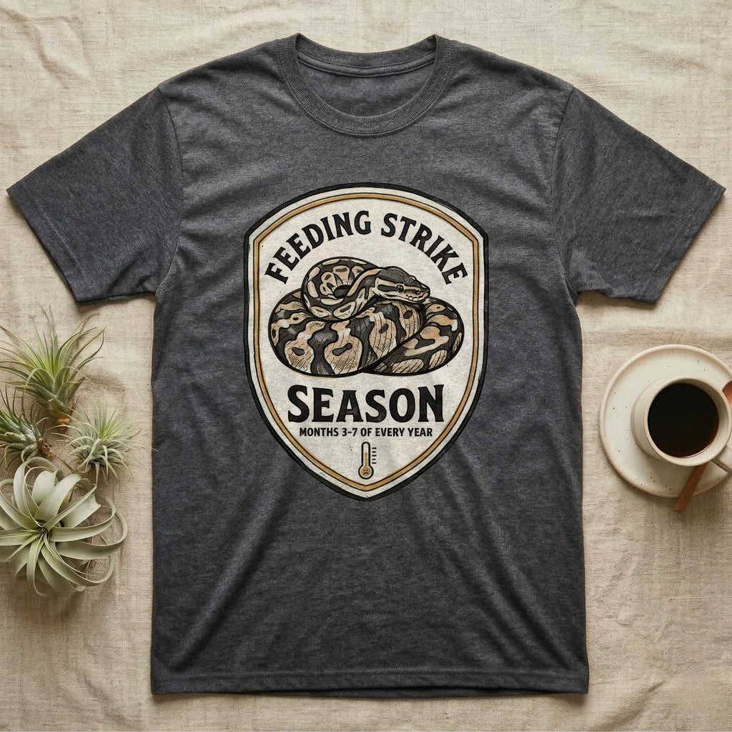 Ball Python Feeding Strike T-Shirt in Dark Heather — Vintage-ink badge of a coiled ball python with carved type "Feeding Strike Season" and fine print "Months 3-7 Of Every Year."