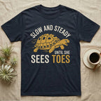 Hermann's Tortoise Toes T-Shirt in Navy — Golden ochre Hermann's tortoise charging to the right under arched cream words Slow And Steady, with Until She Sees Toes below