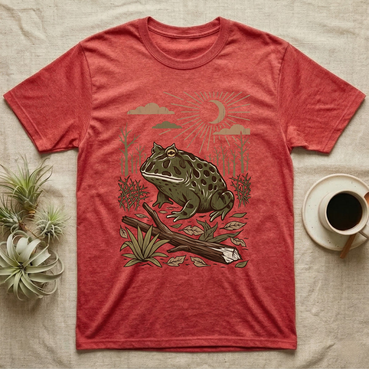 Pacman Frog Home Range T-Shirt in Heather Red — Woodcut-style illustration of a pacman frog sitting on the Chaco forest floor among fallen branches and thorn scrub, no on-shirt text.