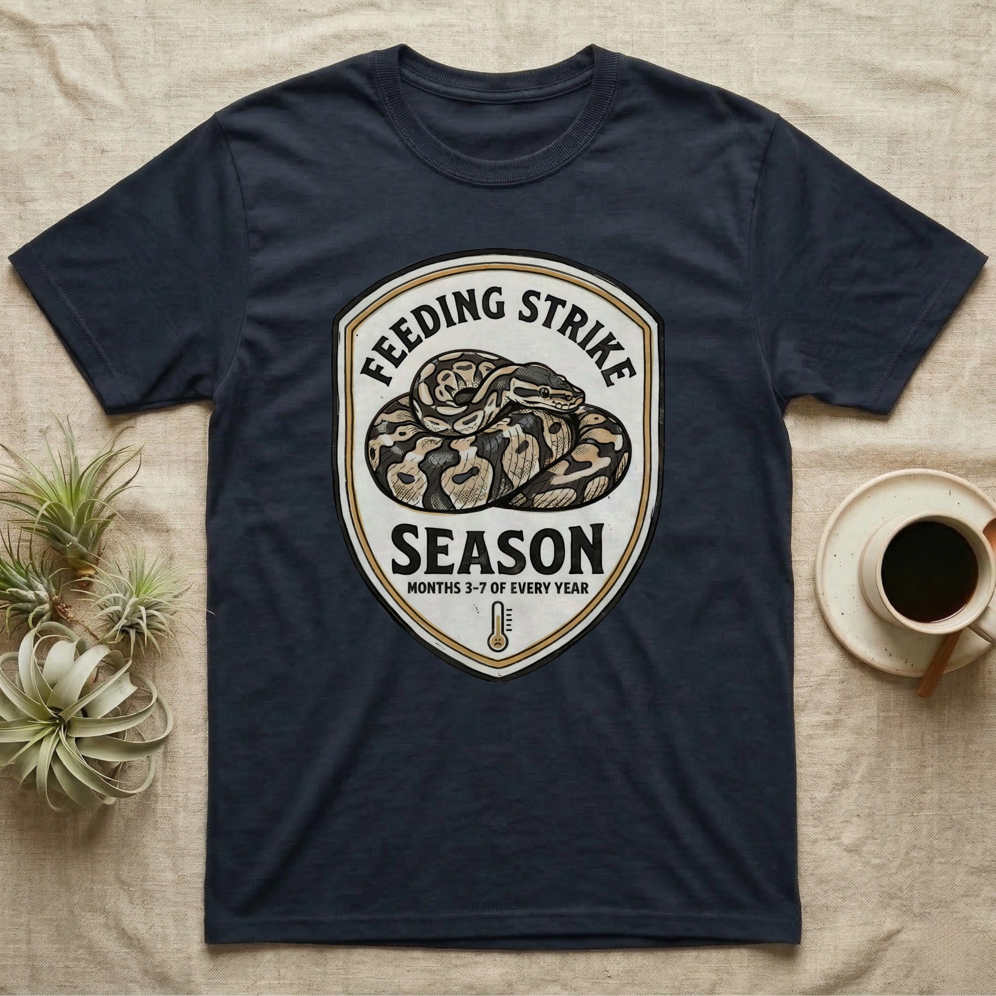 Ball Python Feeding Strike T-Shirt in Navy — Vintage-ink badge of a coiled ball python with carved type "Feeding Strike Season" and fine print "Months 3-7 Of Every Year."