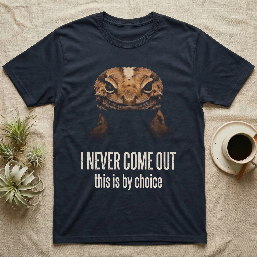 Deadpan photographic mugshot of an African fat-tailed gecko half in shadow above the distressed text I Never Come Out, this is by choice. — shown on a Navy tee.