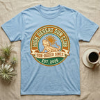 Light blue t-shirt with "High Desert Sun Club" logo featuring a bearded dragon.