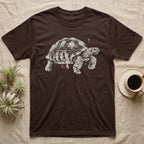Sulcata Bleach Spatter T-Shirt in Dark Chocolate — Sulcata tortoise marching to the right, head up and one scaly front leg mid-step, formed from pale bleach spatter on black.