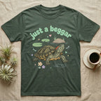 Red-Eared Slider Softie T-Shirt in Military Green — Red-eared slider turtle stretching its neck to beg, under pastel bubble text "just a beggar" with hearts.