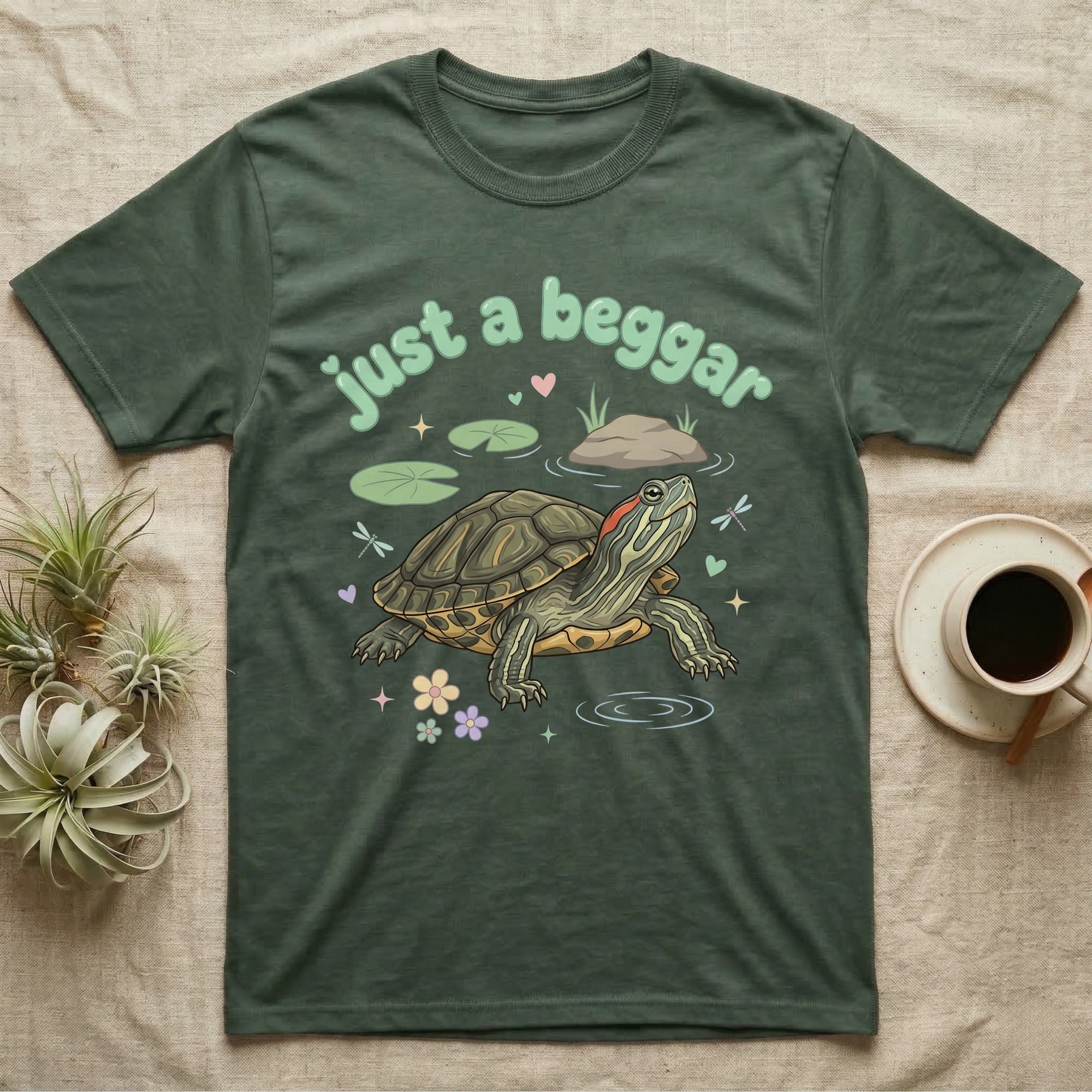 Red-Eared Slider Softie T-Shirt in Military Green — Red-eared slider turtle stretching its neck to beg, under pastel bubble text "just a beggar" with hearts.