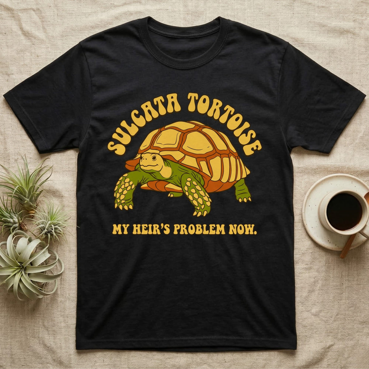 Black t-shirt with a Sulcata tortoise graphic and text "MY HEIR'S PROBLEM NOW."