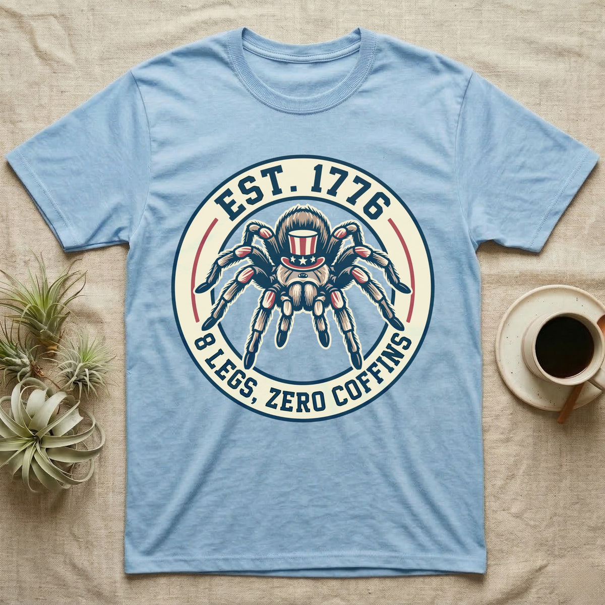 Tarantula Zero Coffins T-Shirt in Light Blue — Circular patch emblem of a tarantula in a top hat with arched text Est. 1776 and 8 Legs Zero Coffins.