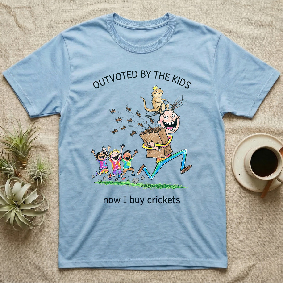 Lizard Dad Outvoted T-Shirt in Light Blue — Crayon drawing of a crowned bearded dragon riding a grinning dad who carries a bag of crickets while three kids cheer, under Outvoted By The Kids, now I buy crickets