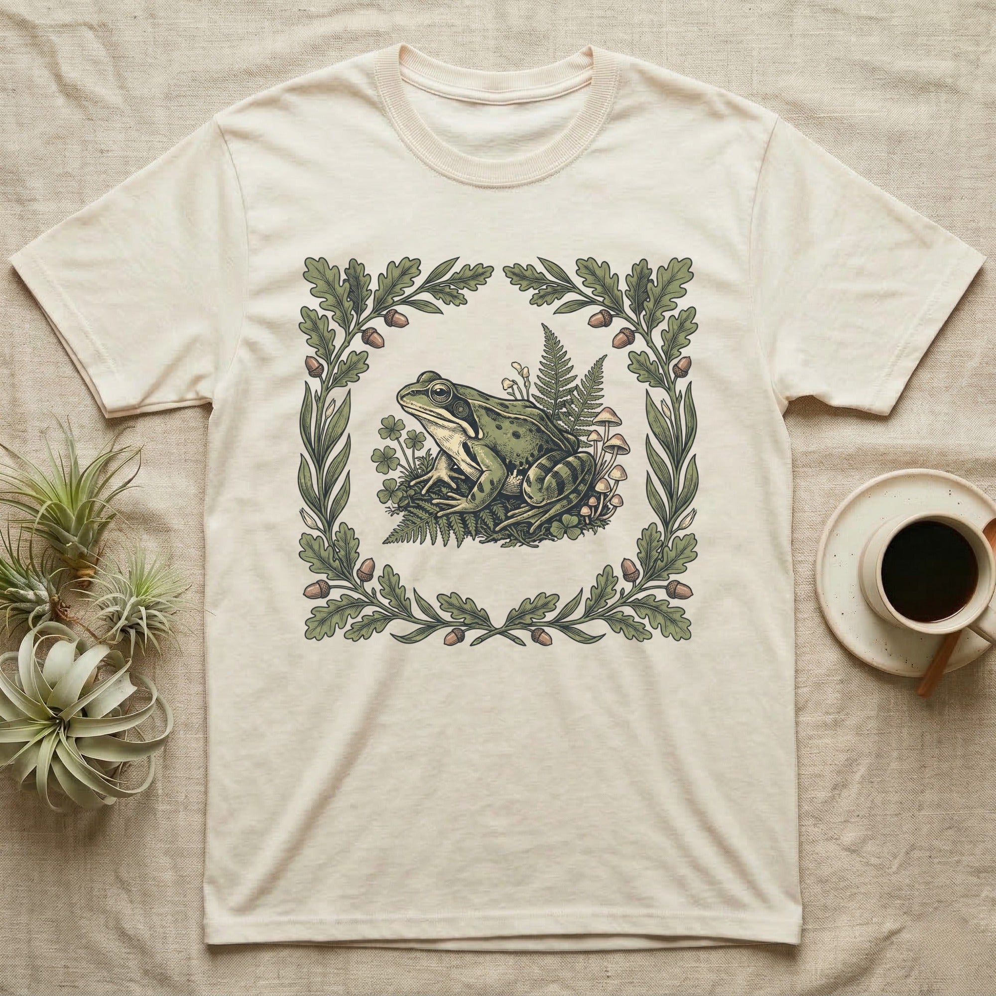 Cream t-shirt with frog, mushrooms, and oak leaf border design.